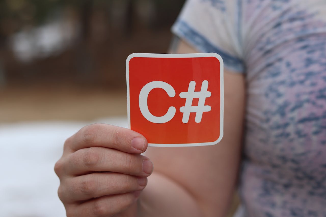 Mastering the First Impression: Your intriguing post title goes here Close-up of a hand holding a C# sticker representing computer programming outdoors.